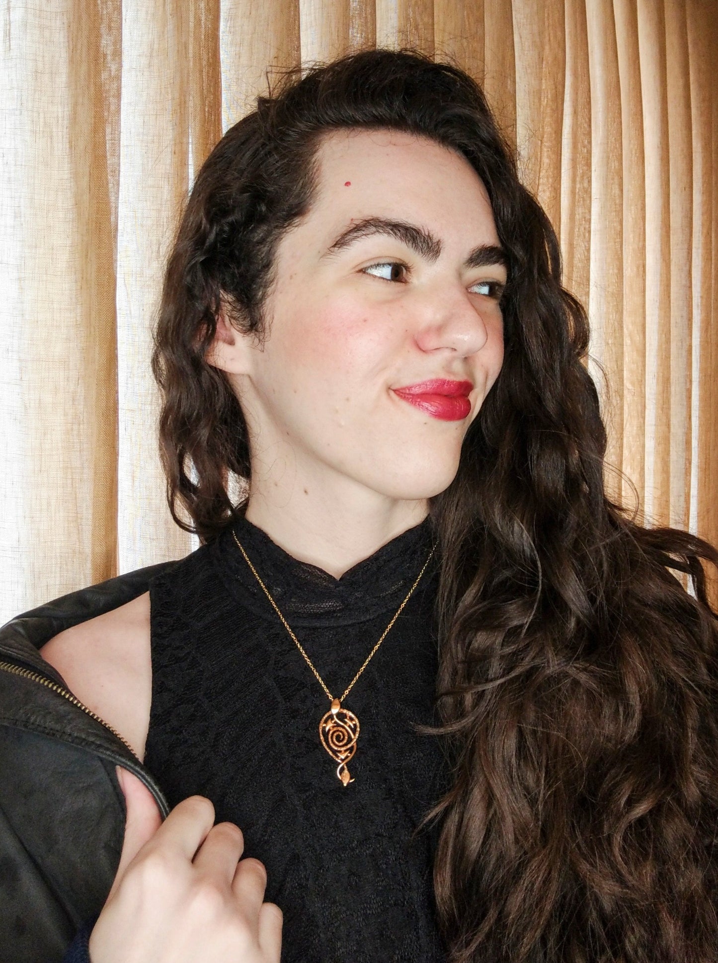 A female model wears the bronze Hypnosis pendant against a black shirt.