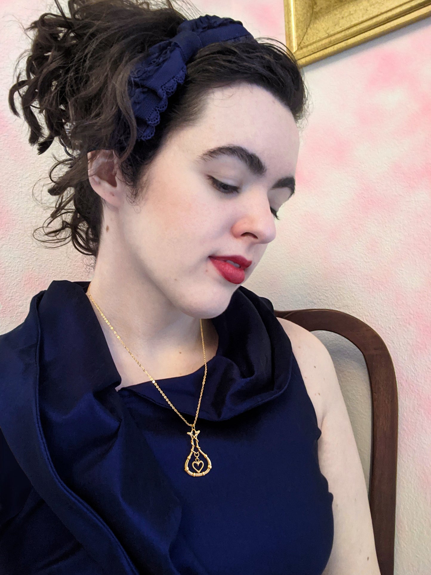 Female model wearing "Love Potion" bronze pendant against a blue dress.