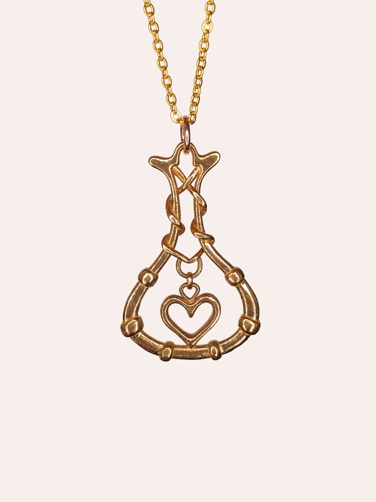A bronze pendant of a heart inside a bottle.