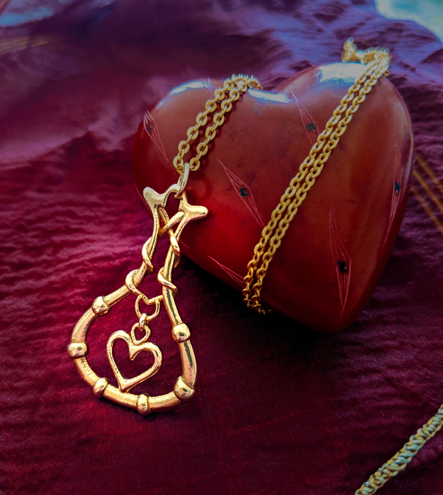 "Love Potion" pendant shown against a red stone heart and red cloth.