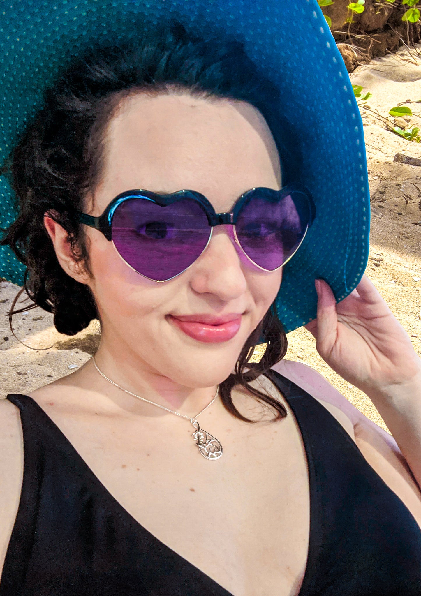 A female model wears the silver Seaside pendant at the beach.
