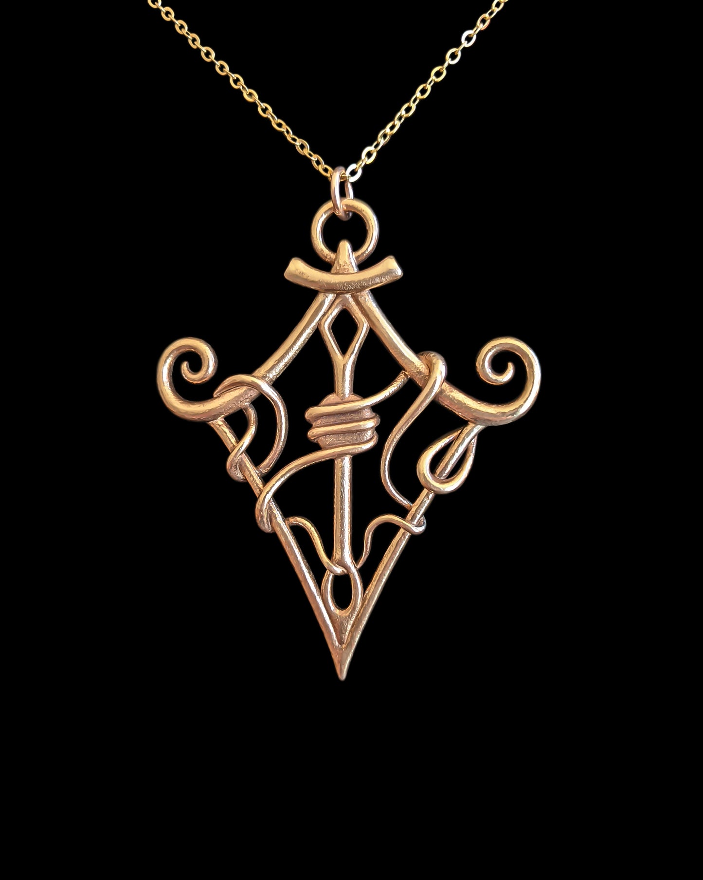 "Through The Eye of the Needle" bronze pendant against a black background.
