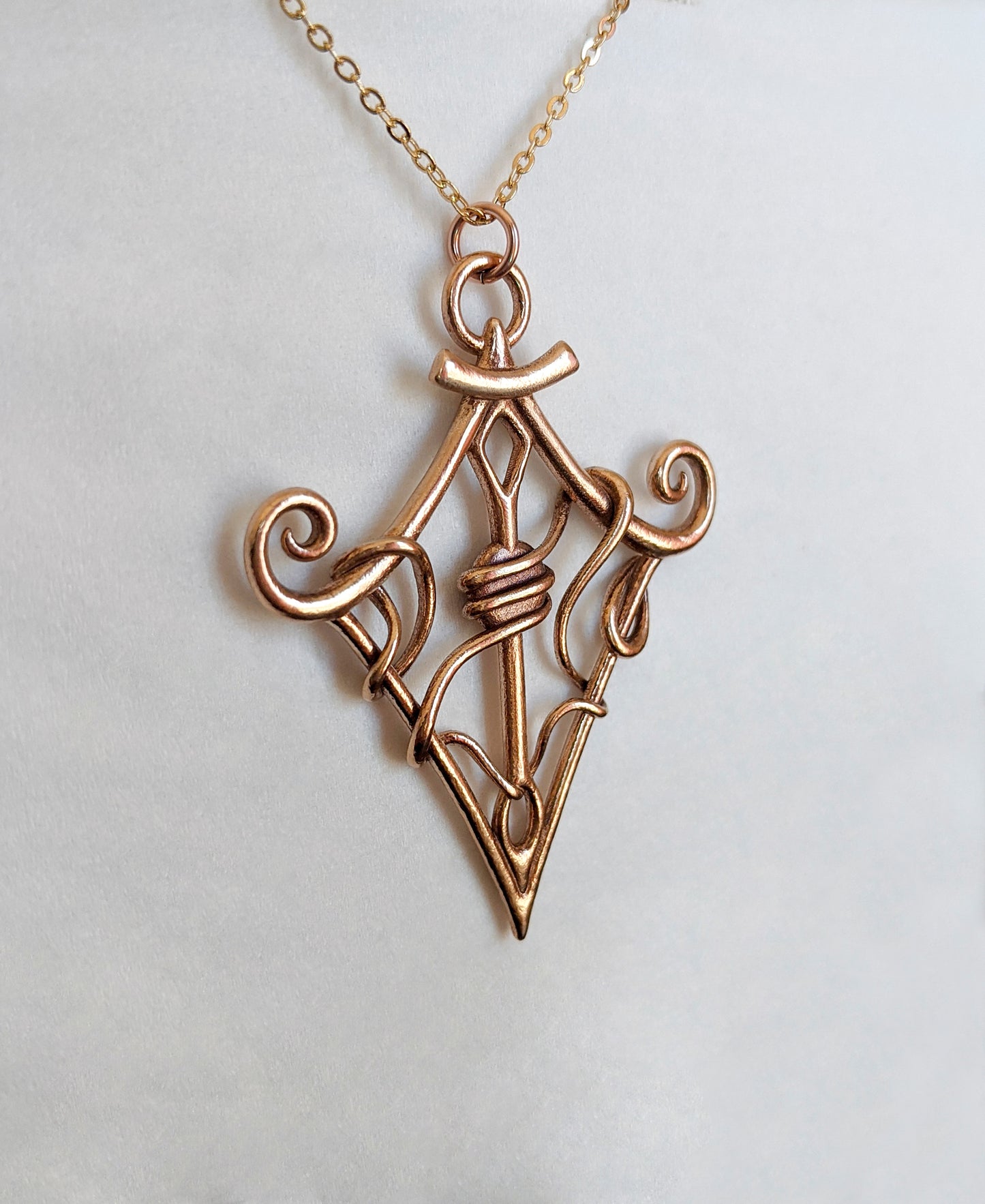 "Through the Eye" bronze pendant shown at an angle against light background.