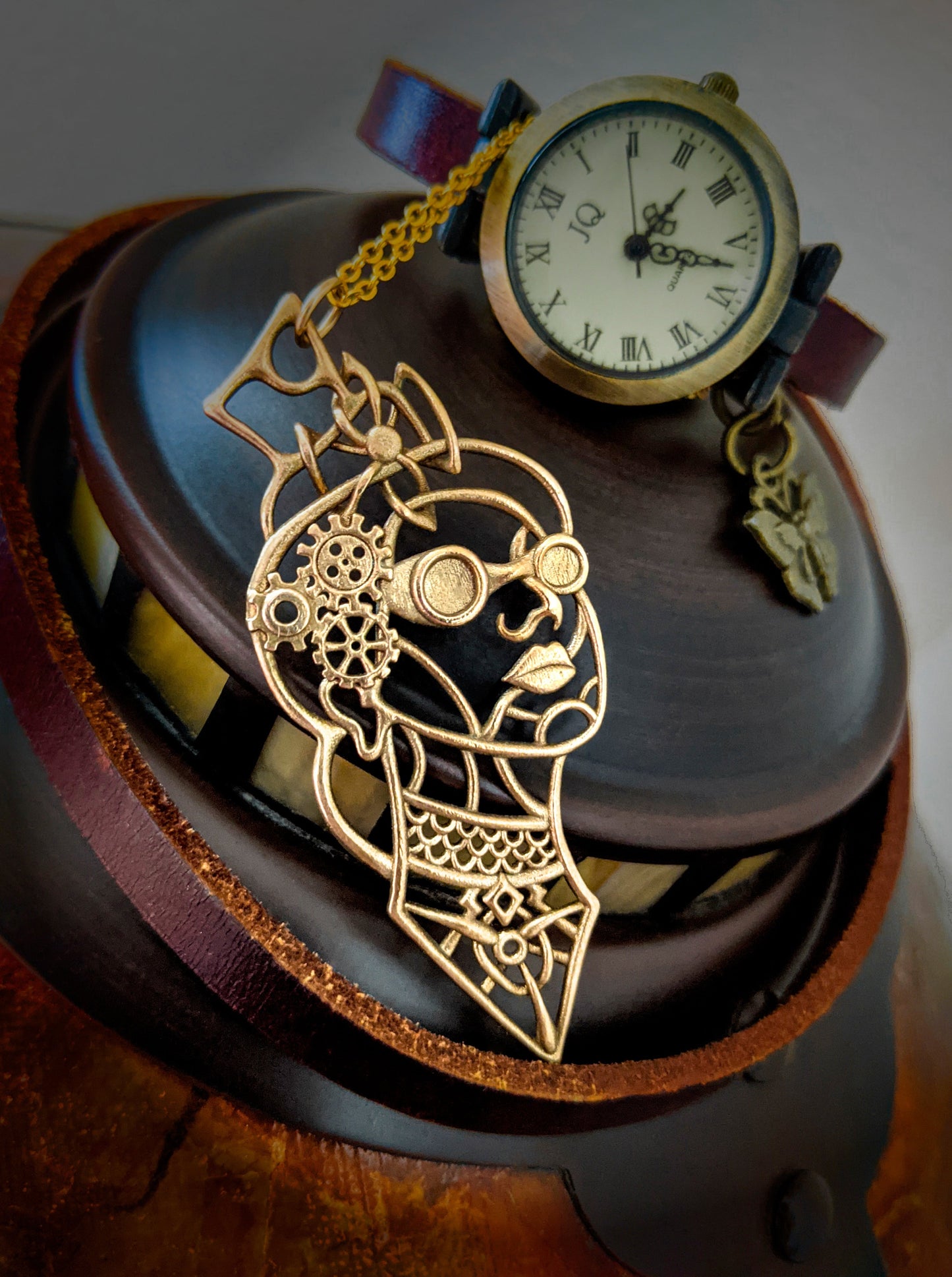 Victoria pendant in bronze with a watch in the background.